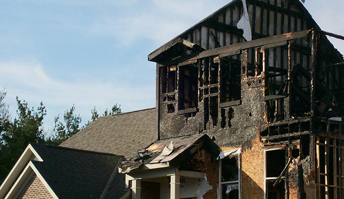 A severely burnt house with charred walls and roof